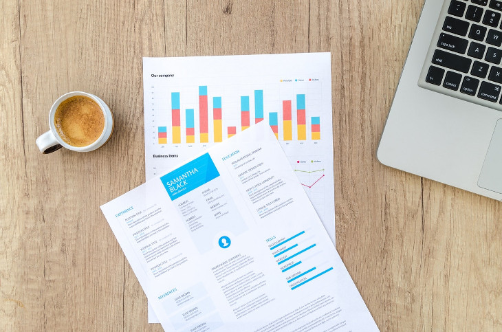 A photo of sheets showing the revenue numbers and a cup of coffee